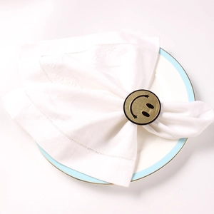 Creative gold smiley face napkin ring set on a white linen napkin for table setting