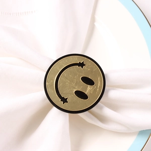 Golden smiley face napkin ring with star eyes on white cloth for hotel table setting