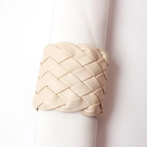 Detail of hand-woven beige leather napkin ring showing texture on white fabric