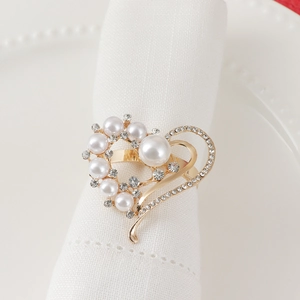 Golden heart napkin ring with pearls and rhinestones on a white linen table setting