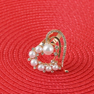 Golden heart napkin ring with pearls and rhinestones on a red textured background