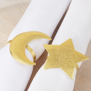 Detail of gold star and moon napkin rings with frosted texture on white fabric