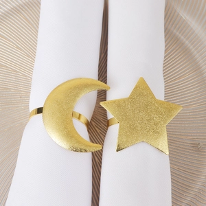 Elegant gold matte star and moon napkin rings set on white cloth and golden textured plate