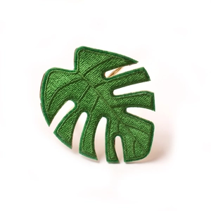 Handcrafted Monstera leaf napkin ring with green embroidery and golden metal loop