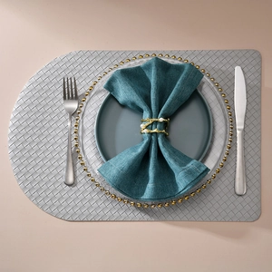 Gold plant branch napkin ring with pearls on dark teal napkin and woven placemat set
