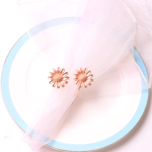 Rose gold daisy napkin rings with floral design on a white ceramic plate for table decor