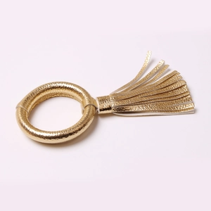 Dettaglio di un portatovagliolo in pelle PU dorata con nappa decorativa pendente