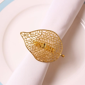 Rond de serviette en forme de feuille dorée ajourée sur serviette blanche pour mariages