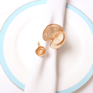 Rond de serviette doré en forme de U avec fleurs et perle sur une assiette