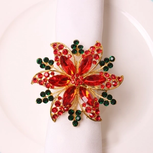 Rond de serviette fleur dorée de Noël avec strass rouges sur une serviette blanche