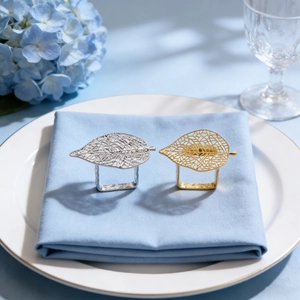 Rond de serviette feuille ajourée dorée sur serviette bleue pour décor de table mariage