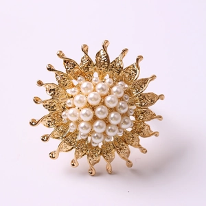Detailed view of a golden sunflower napkin ring with centered pearls and textured petals