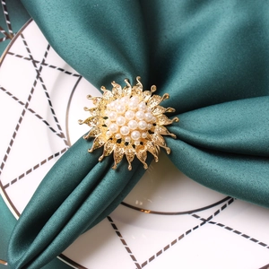 Detailed macro view of golden sunflower napkin ring with pearls on green fabric