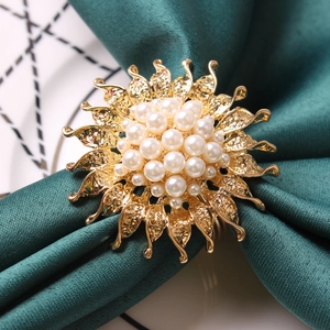 Macro detail of sunflower napkin ring with golden petals and pearl center on green silk