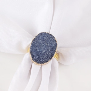 Rond de serviette doré luxueux avec pierre de druzy bleu foncé sur serviette blanche