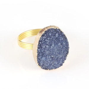Gros plan détaillé d'un cristal druzy bleu sur un anneau multi-rangs en métal plaqué or