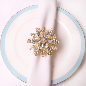 Elegant gold flower napkin ring with crystals on a white napkin and ceramic plate