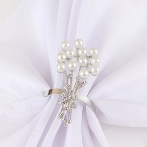 Rond de serviette en métal argenté avec perles et nœud en strass sur tissu blanc