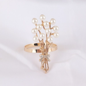 Gros plan d'un rond de serviette doré avec bouquet de perles et détail de nœud en strass