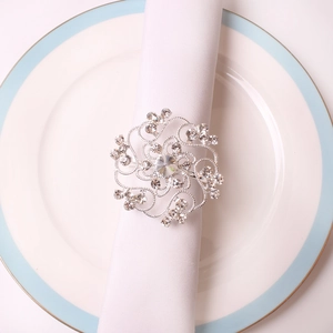 Elegant silver hollow flower napkin ring with sparkling rhinestones on white napkin