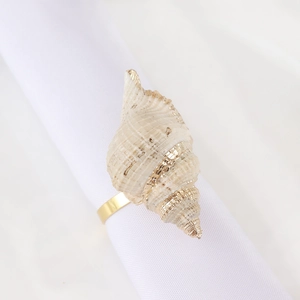 Elegant conch napkin ring with gold finish on white cloth for coastal table decor