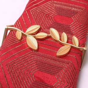 Close-up of golden leaf metal clasp on red embroidered fabric evening clutch bag