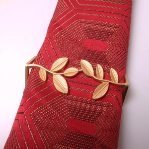 Detailed macro view of matte gold metal leaf napkin ring with intricate vein textures