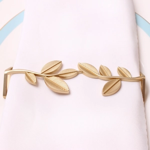 Detail of matte gold leaf napkin ring on a white linen napkin for wedding decor