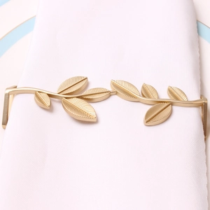 Close-up of matte gold leaf napkin ring with intricate vein details on a white cloth