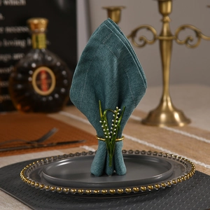 Elegant lily of the valley napkin ring with white pearls on a dark teal linen cloth