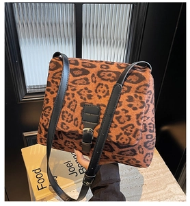 Detail of leopard print shoulder bag featuring black leather strap and silver metal buckle