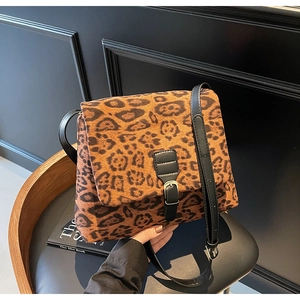 Close-up of leopard print crossbody bag with black leather strap and metal buckle detail
