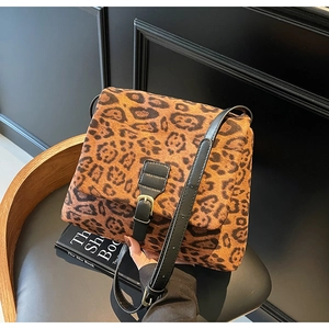 Close-up of leopard print shoulder bag with black leather straps and gold metal buckle