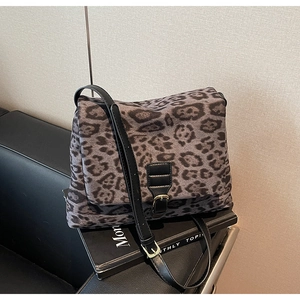 Detailed macro view of gray leopard print bag with black leather strap and metal buckle