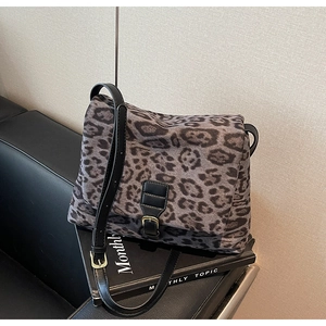 Detail view of leopard print shoulder bag with black leather strap on a textured sofa