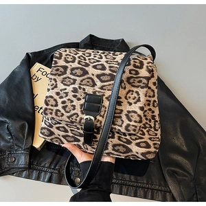 Detail of leopard print crossbody bag with black leather strap on a leather jacket