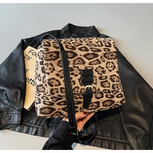 Detail of leopard print crossbody bag with black leather strap and metal buckle accent