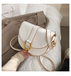 Detailsicht der weißen Satteltasche mit braunem Rand und goldener Hufeisenschnalle