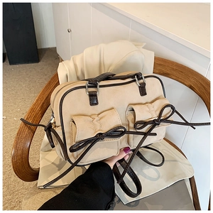 Détail du sac à main rétro en daim beige avec garniture en cuir brun et nœuds décoratifs