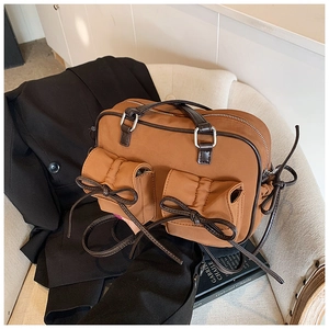 Détail d'un sac à main en nylon marron avec poches à nœuds posé sur un blazer