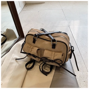 Détail du sac vintage mat beige avec deux poches avant et des accents de sangle marron