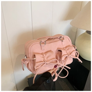 Détail d'un sac à main en toile rose avec poches plissées et nœuds décoratifs élégants