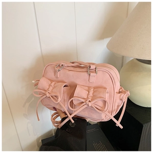 Détail d'un sac à main en cuir rose avec nœuds décoratifs et boucles en métal argenté