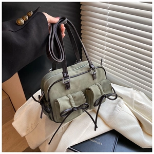 Détail du sac Boston en daim vert avec finitions en cuir marron et nœuds décoratifs