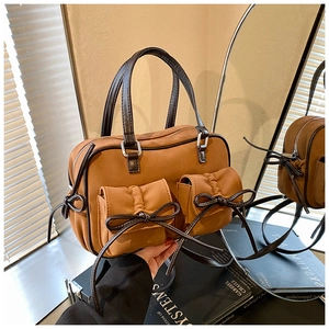 Détail du sac Boston marron caramel avec poches à nœuds et poignées en cuir lisse