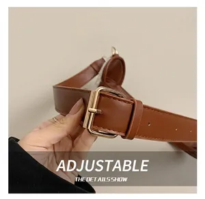 Detail of adjustable brown leather shoulder strap with a golden metal buckle