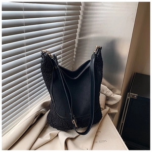 Detail of black contrast tote bag featuring lamb wool trim and golden metal buckles