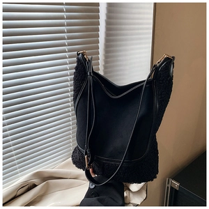 Detail of black contrast bucket bag featuring sherpa texture and gold metal hardware