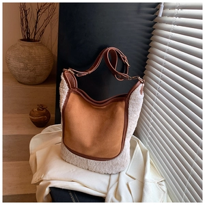 Detail of hobo bucket bag with brown suede and white faux shearling trim with gold hardware