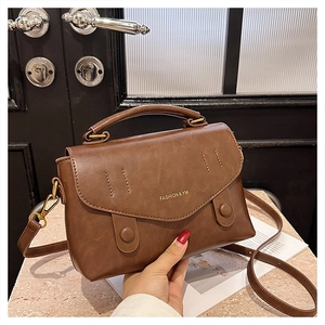 Detail of vintage brown leather handbag with fashion lettering and gold-toned hardware